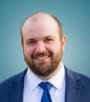 Picture of NIAC member Kristopher Ravin, a man with a beard and a blue tie.